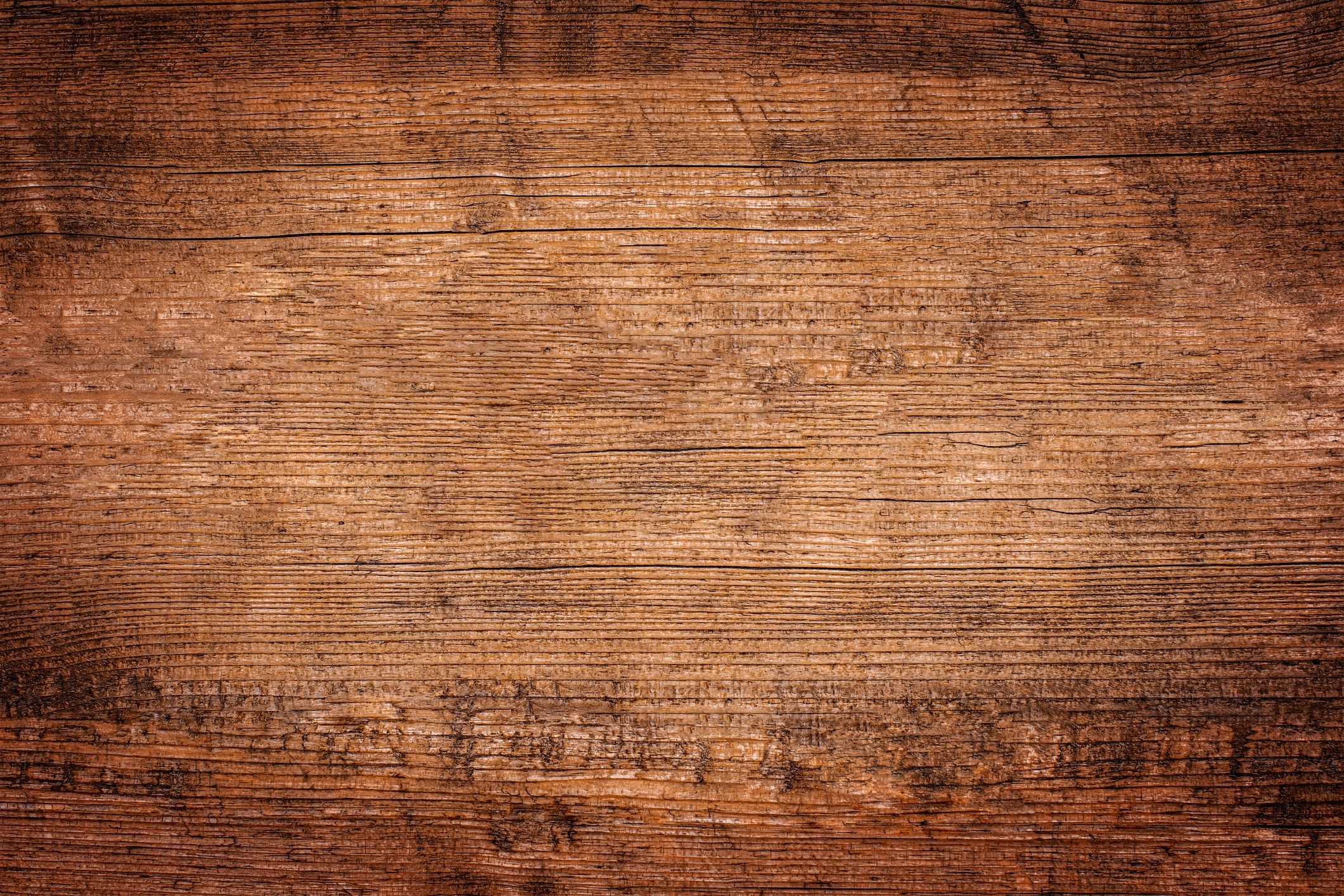 Close-up of a rustic, textured wooden surface with visible grain and knots, suggesting an aged and weathered plank used for flooring or furniture.